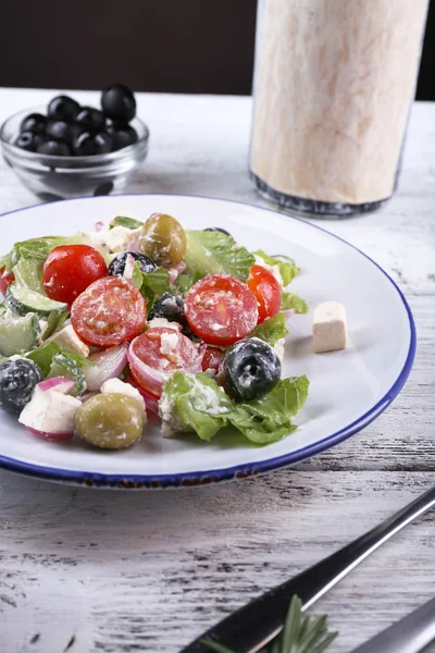 Plate of Greek salad served with olives on wooden table on dark background — Stock Photo, Image