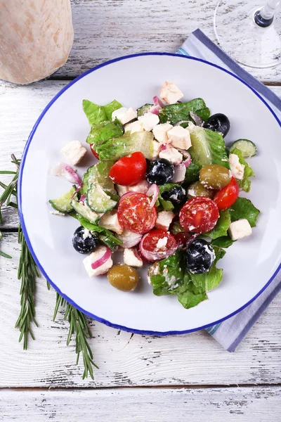 Plate of Greek salad served on napkin on wooden background — Stock Photo, Image