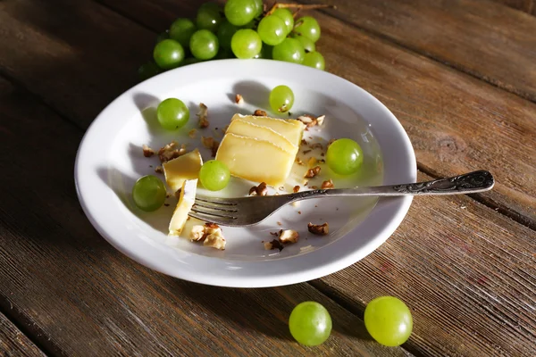 Lezzetli üzüm ve ahşap masa üzerinde plaka üzerinde peynir — Stok fotoğraf
