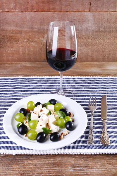 Hermosa naturaleza muerta con vino y ensalada sobre fondo de madera —  Fotos de Stock