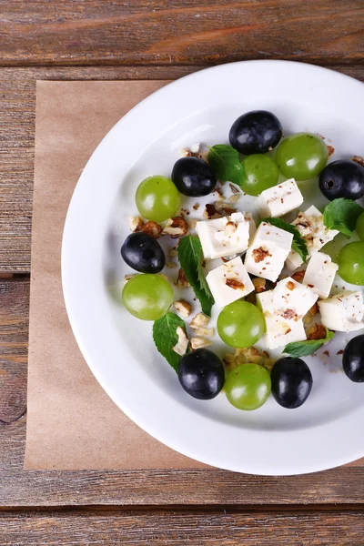 Gustosa insalata con uva e formaggio sul tavolo di legno — Foto Stock