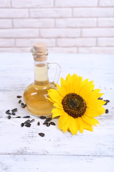 Sunflower with seeds and oil on table on brick wall background — Stock Photo, Image