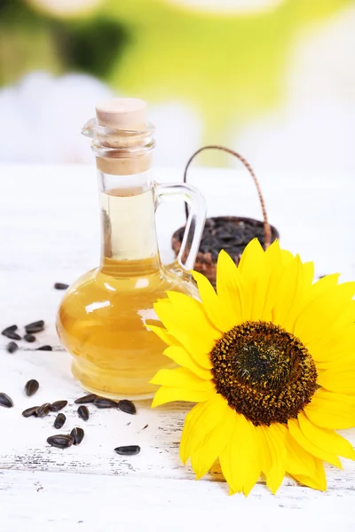 Sunflower with seeds and oil on table on bright background — Stock Photo, Image