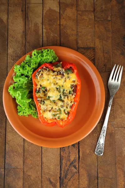 Stuffed red pepper with lettuce on plate on wooden table — Stock Photo, Image