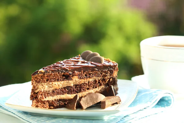 Chokladkaka på plattan och kopp te på bordet, på ljus bakgrund — Stockfoto