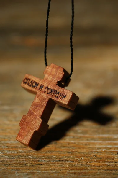 Wooden cross with deep shadow on wooden background — Stock Photo, Image