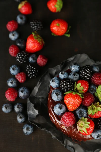 Chutný čokoládový dort s různými plody na dřevěný stůl — Stock fotografie