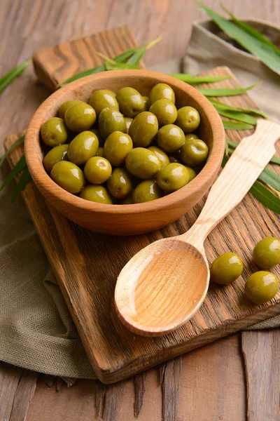 Green olives in bowl with leaves on table close-up — Stock Photo, Image