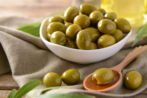 Gröna oliver i skål med blad på tabell närbild — Stockfoto