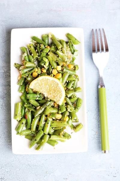 Salade aux haricots verts et maïs, graines de sésame sur assiette, sur fond de bois couleur — Photo