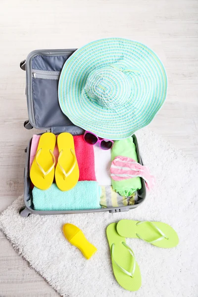 Suitcase with things on white carpet on the floor for travelling somewhere close to water for spending summer vacation — Stock Photo, Image