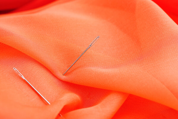 Иглы на фоне цветной ткани
