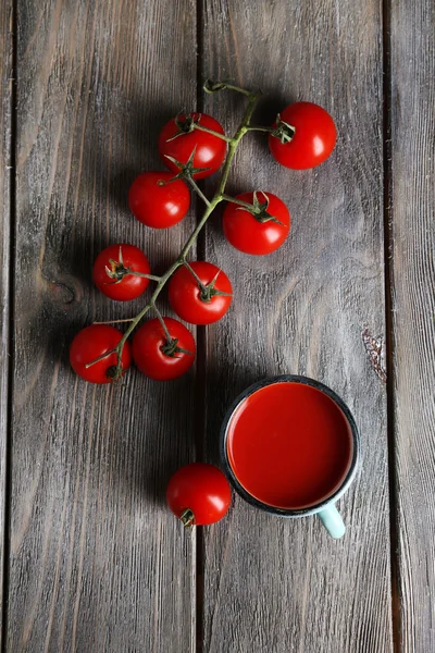 Homemade tomato juice in color mug and fresh tomatoes on wooden background — Stock Photo, Image