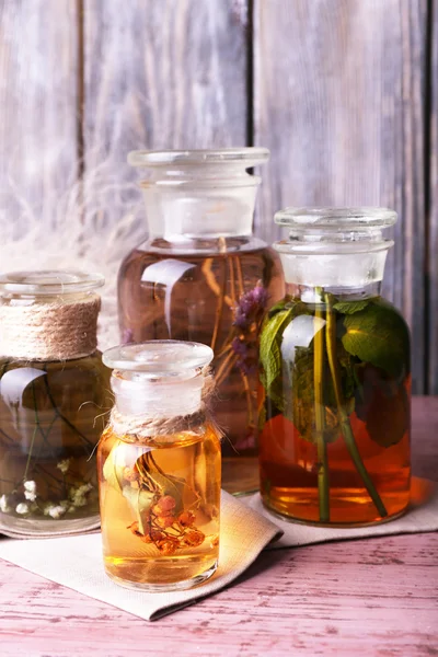 Bottles of herbal tincture on a napkin on  wooden table in front of wooden wall — Stock Photo, Image