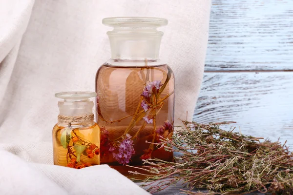 Flessen van tinctuur en gedroogde kruiden op een servet op houten achtergrond voor gordijn — Stockfoto