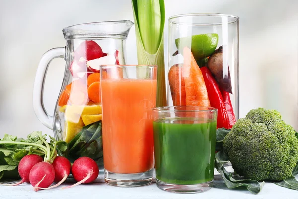 Kruik van gesneden groenten en glas verse groentesap met groenten op houten tafel — Stockfoto