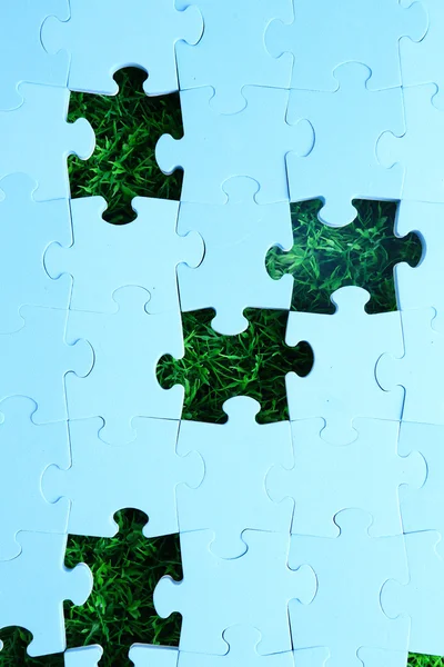 Puzzle pezzi su sfondo erba verde. Concetto spazio verde — Foto Stock