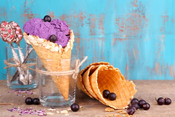 Gustoso gelato con bacche in coni di cialde su sfondo blu in legno — Foto Stock