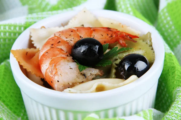 Fresh prawns with coloured macaroni and olives in a round bowl on a green napkin on wooden background — Stock Photo, Image