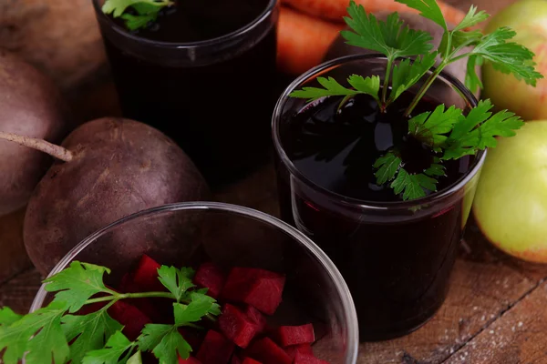 Vasos de jugo de remolacha fresca y verduras sobre fondo de madera — Foto de Stock