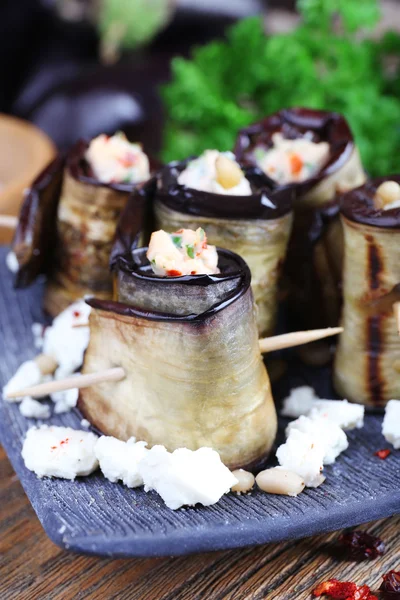 Fried aubergine with cottage cheese in a square plate on wooden cutting board on wooden background — Stock Photo, Image