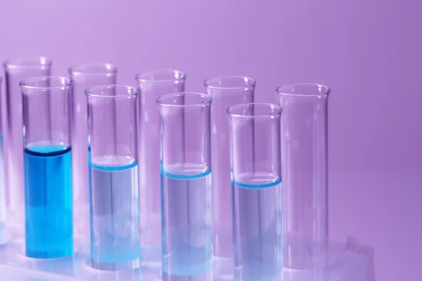 Test-tubes with blue liquid on purple background — Stock Photo, Image