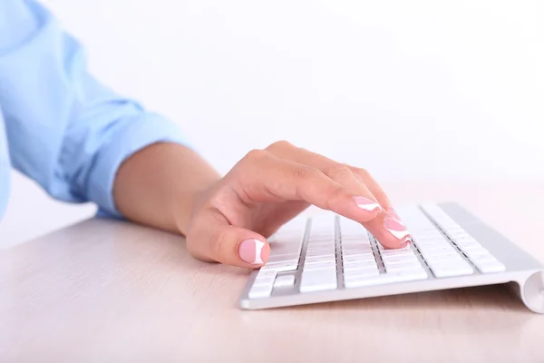 Mãos femininas digitando no teclado, close-up, no fundo claro — Fotografia de Stock