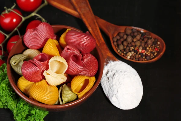 Composição de macarrão colorido em tigela, tomates frescos, salsa em fundo de madeira escura — Fotografia de Stock