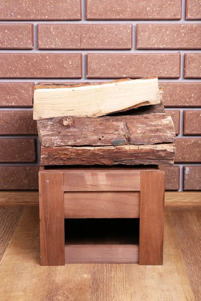 Caixa de madeira de lenha no chão sobre fundo de tijolo — Fotografia de Stock