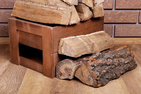 Деревянная коробка дров на полу на кирпичном фоне — стоковое фото