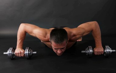 yakışıklı genç kaslı sporcu, koyu arka plan üzerinde egzersiz halter ile yürütmek