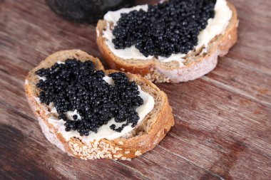 tereyağı ve ahşap arka plan üzerinde siyah havyar ile ekmek dilimleri