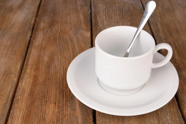 Empty cup with tea spoon on wooden background — Stock Photo, Image