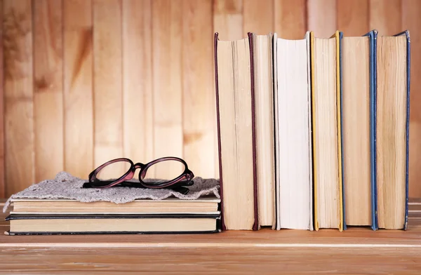 Bücher auf Holztisch auf hölzernem Wandhintergrund — Stockfoto