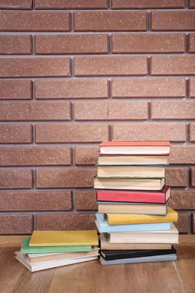Libros sobre mesa de madera sobre fondo de pared de ladrillo —  Fotos de Stock