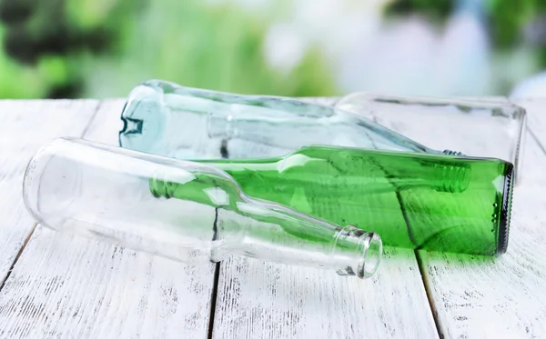 Botellas de vidrio vacías en la mesa sobre fondo brillante — Foto de Stock