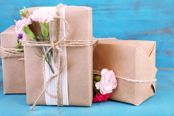 Prachtige geschenken met bloemen, op oude houten achtergrond — Stockfoto