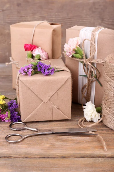 Красиві подарунки з квітами та декоративною мотузкою на старому дерев'яному тлі — стокове фото