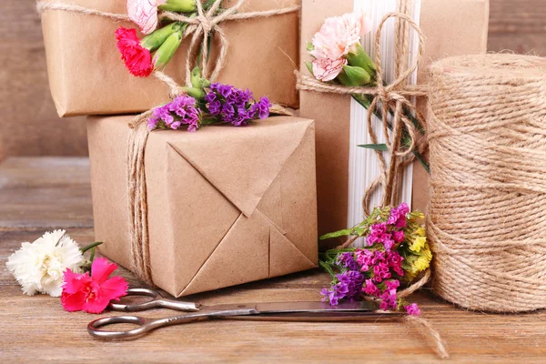 Beaux cadeaux avec des fleurs et une corde décorative, sur un vieux fond en bois — Photo