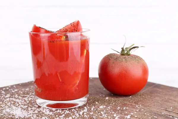 Vidro de suco de tomate com especiarias e tomates frescos na mesa de madeira — Fotografia de Stock