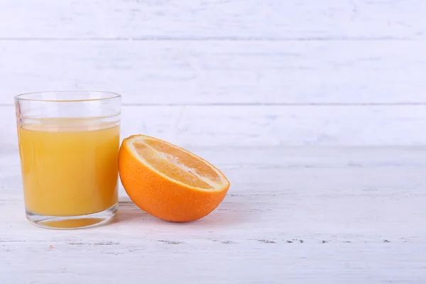 Vaso de jugo y sabrosa naranja sobre mesa de madera — Foto de Stock