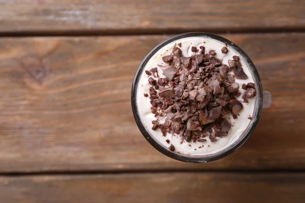 Yoghurt, med choklad grädde, hackad choklad och müsli serveras i glas på trä bakgrund — Stockfoto