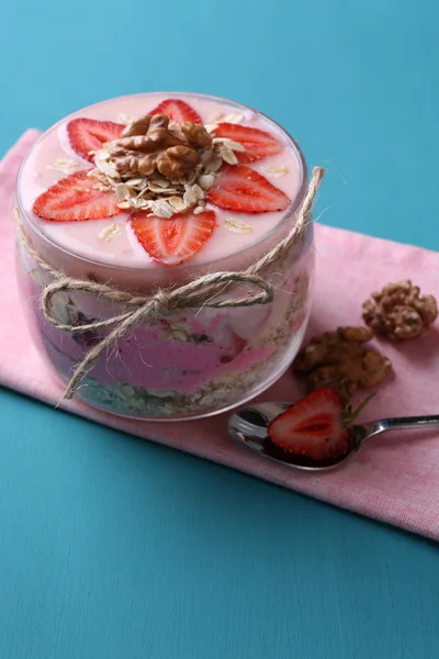 Healthy breakfast - yogurt with  strawberries and muesli served in glass jar, on color wooden background — Stock Photo, Image