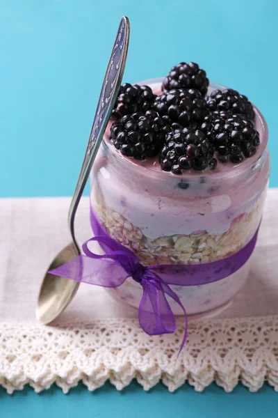 Healthy breakfast - yogurt with  blackberries and muesli served in glass jar, on color wooden background — Stock Photo, Image