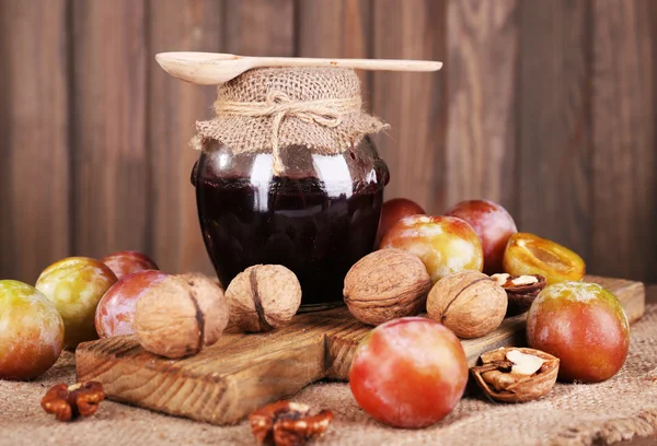 Confiture de prunes savoureuse en pot et prunes sur table en bois close-up — Photo