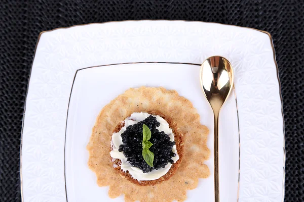 Caviar negro con pan crujiente en plato sobre fondo de tela oscura —  Fotos de Stock