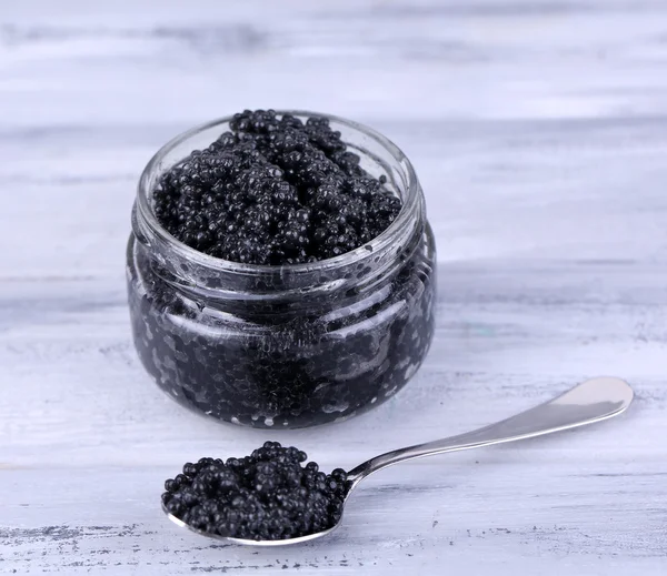 Tarro de vidrio y cuchara de caviar negro sobre fondo de madera gris —  Fotos de Stock