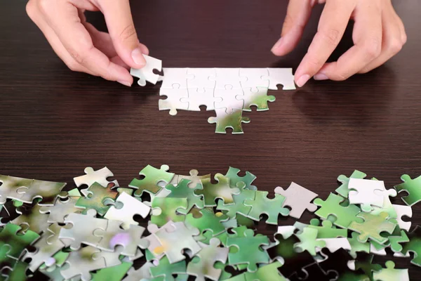 Hand hält Puzzleteil auf Holztischhintergrund — Stockfoto