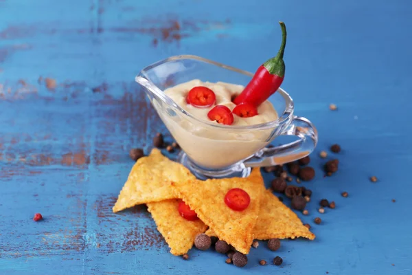 Nachos saborosos e tigela com molho na cor de fundo de madeira — Fotografia de Stock