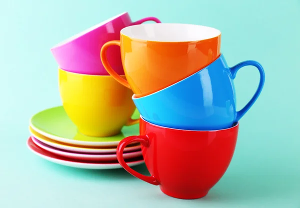 Bunte Tassen und Untertassen auf farbigem Hintergrund — Stockfoto